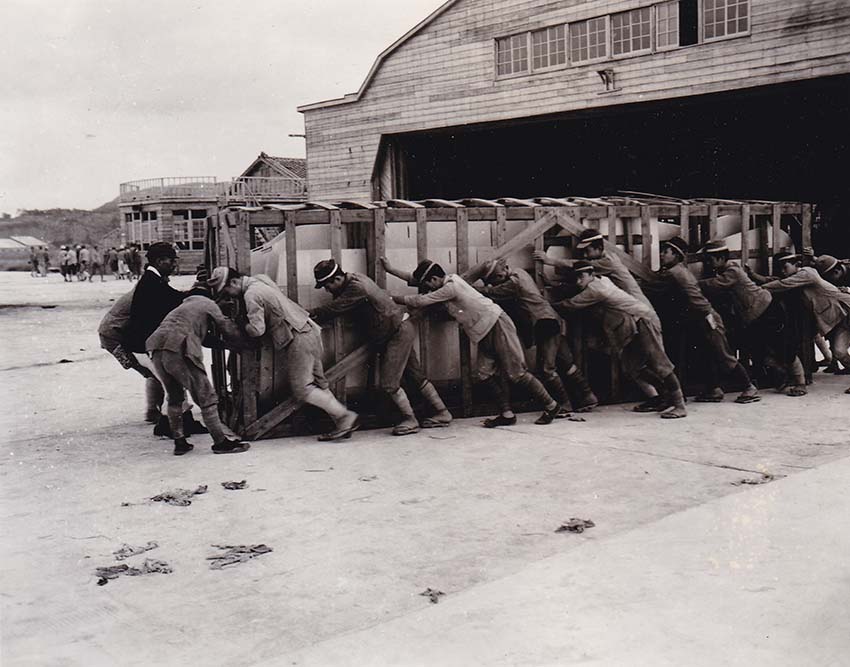 格納庫から水上機の翼を出す学生