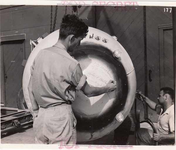 塗装中の長崎原爆ファットマンにメッセージを書くラムジー博士